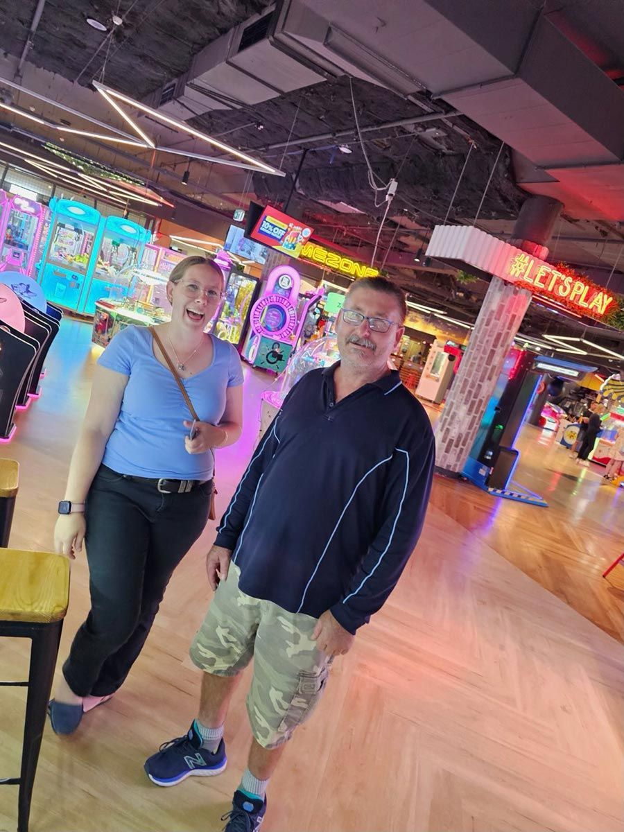 A Man and A Woman Are Standing Next to Each Other in An Arcade — Comfort N Care Support QLD Pty Ltd In Highfields, QLD