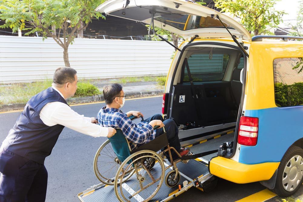 Driver Helping Man On A Wheelchair Getting Into Transport — Comfort N Care Support QLD Pty Ltd In Toowoomba City, QLD