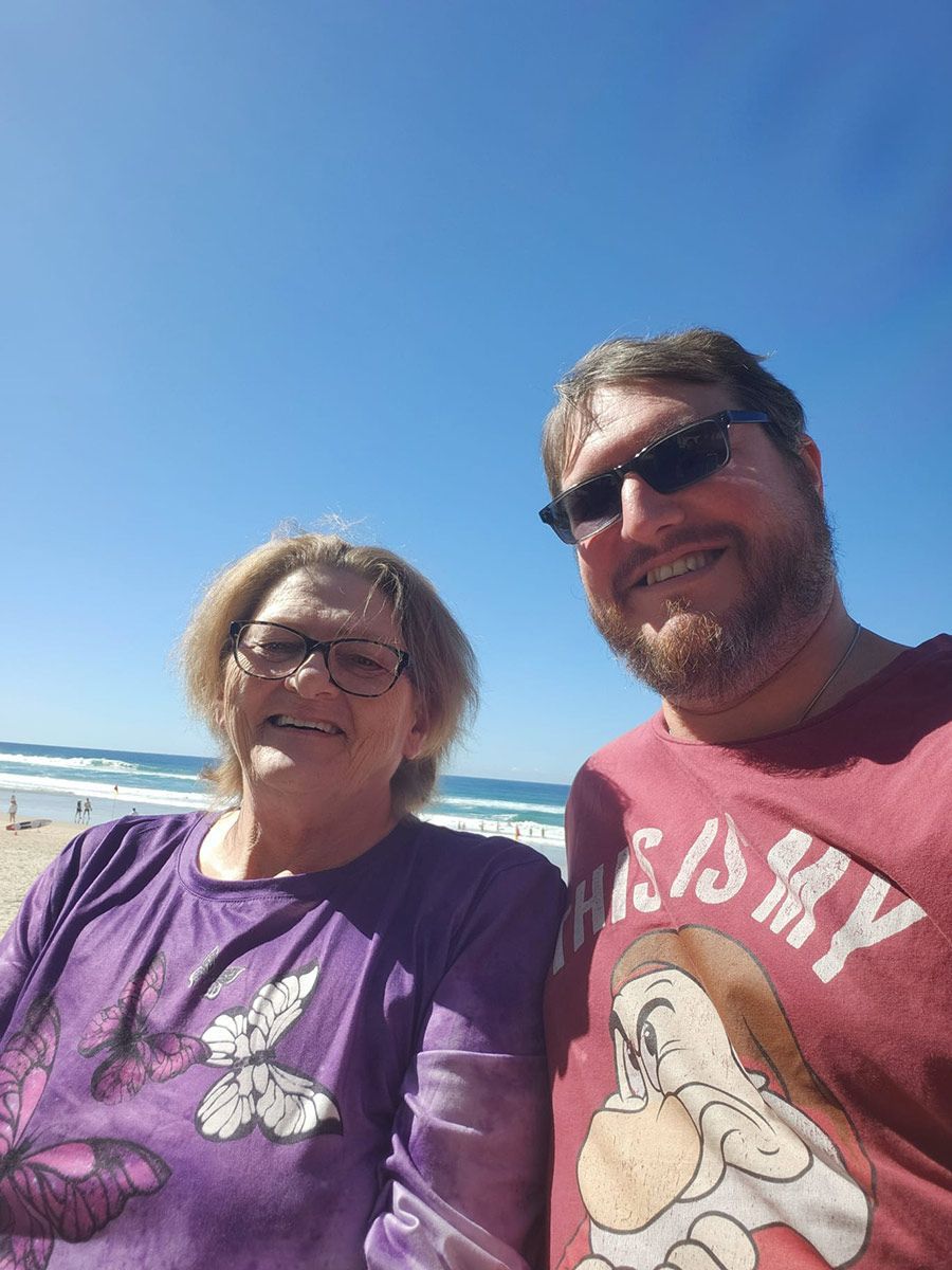 A Man and A Woman Are Posing for A Picture on The Beach — Comfort N Care Support QLD Pty Ltd In Toowoomba City, QLD