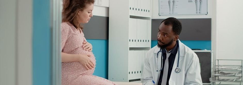 Uma mulher grávida está conversando com um médico em um quarto de hospital.