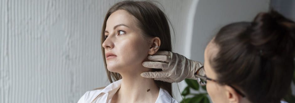 Uma mulher está tendo o pescoço examinado por um médico.