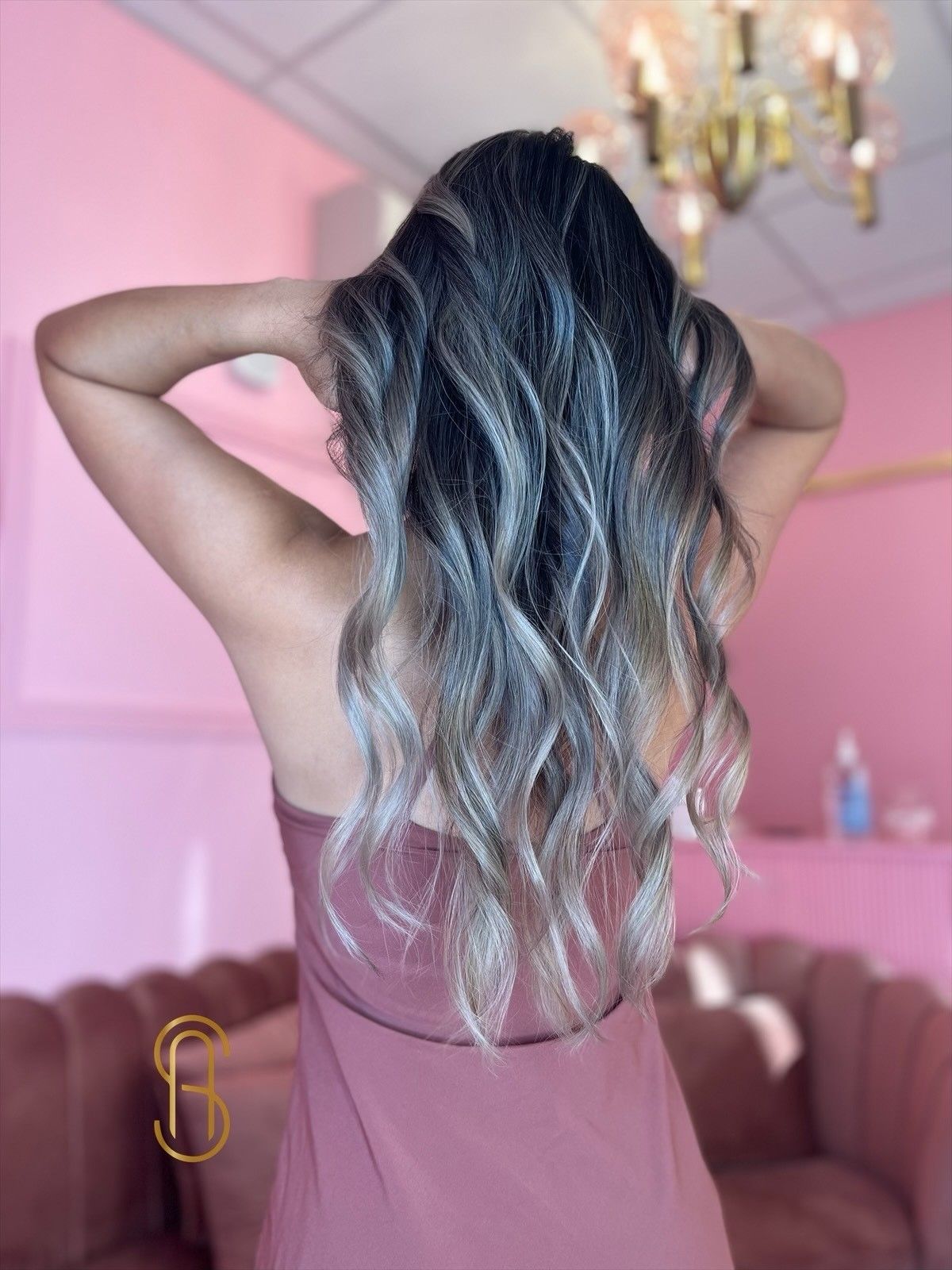 A woman in a pink dress is standing in front of a pink wall.