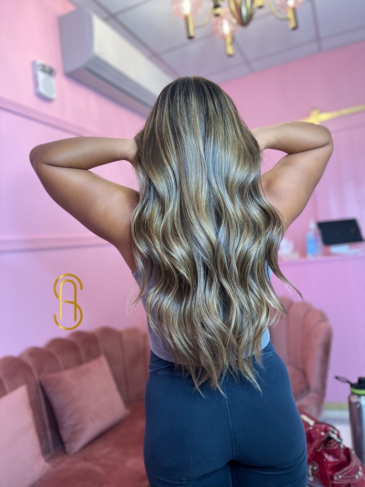 A woman with long hair is standing in front of a pink couch.