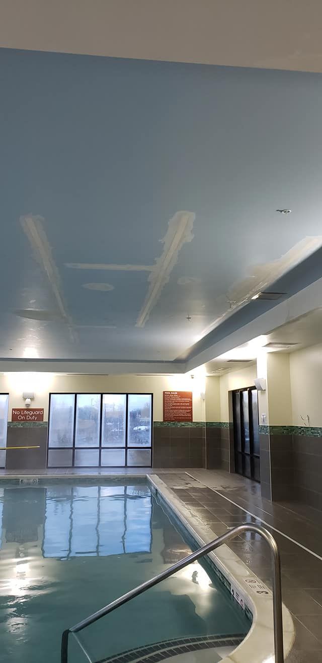 An indoor swimming pool with a blue ceiling and stairs leading to it.