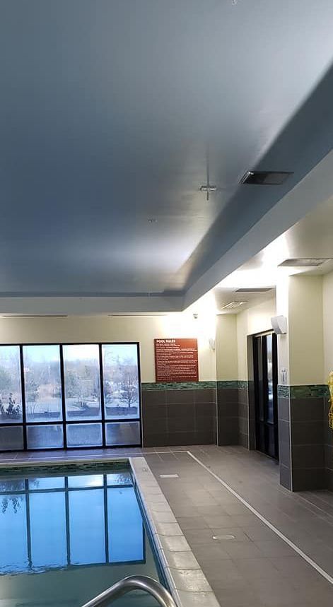 There is a large indoor swimming pool with a lot of windows.