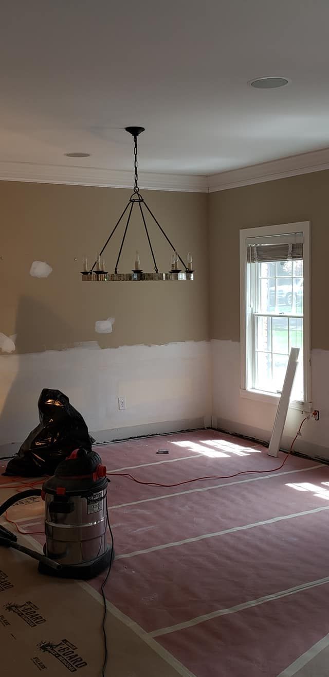A room with a vacuum cleaner on the floor and a chandelier hanging from the ceiling.