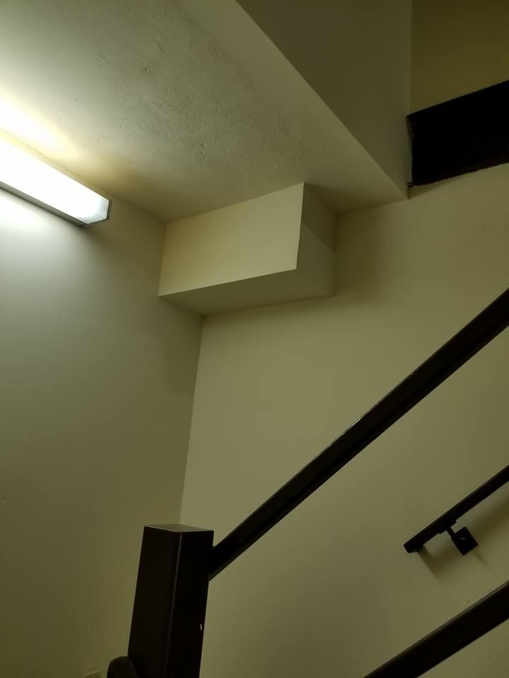A staircase with a white wall and a black railing