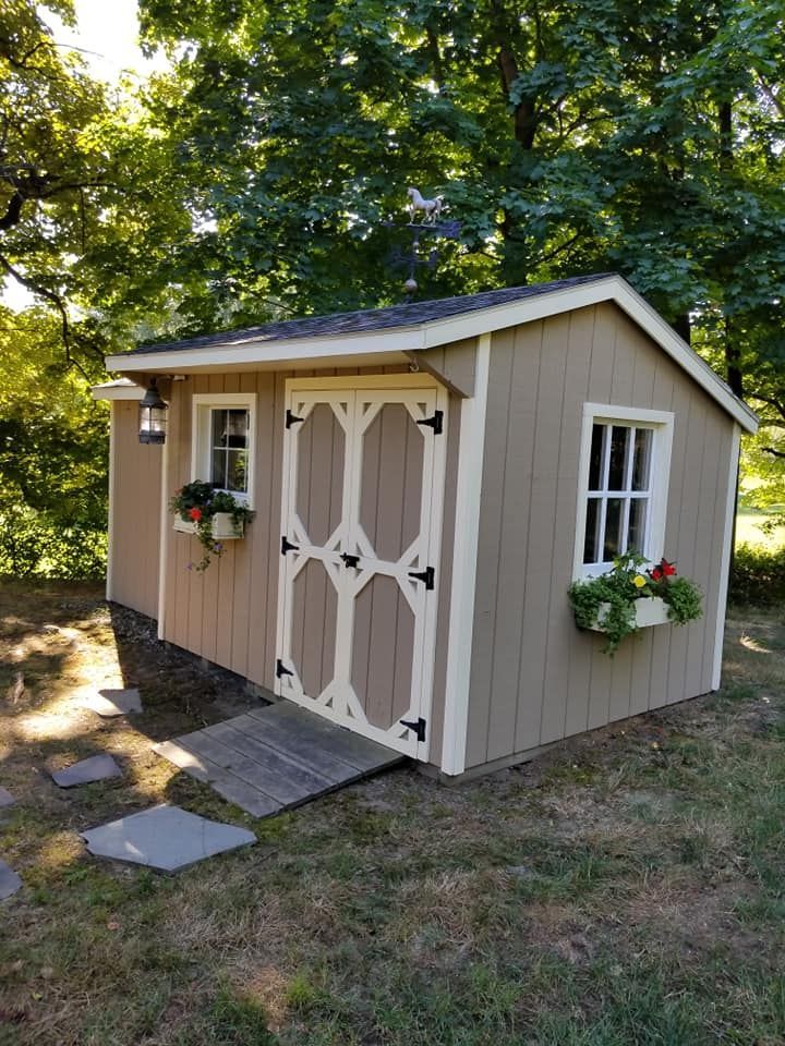 A small shed with a ramp leading to it is sitting in the middle of a lush green field.