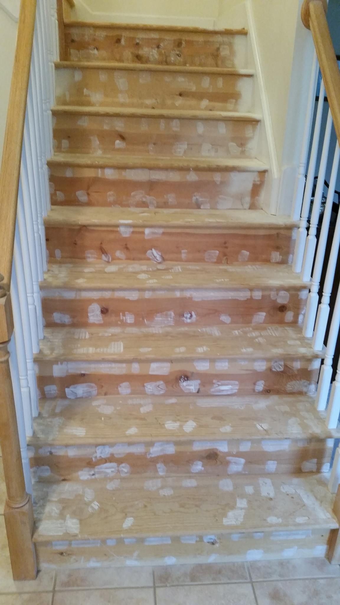 A wooden staircase with a white railing is being painted.