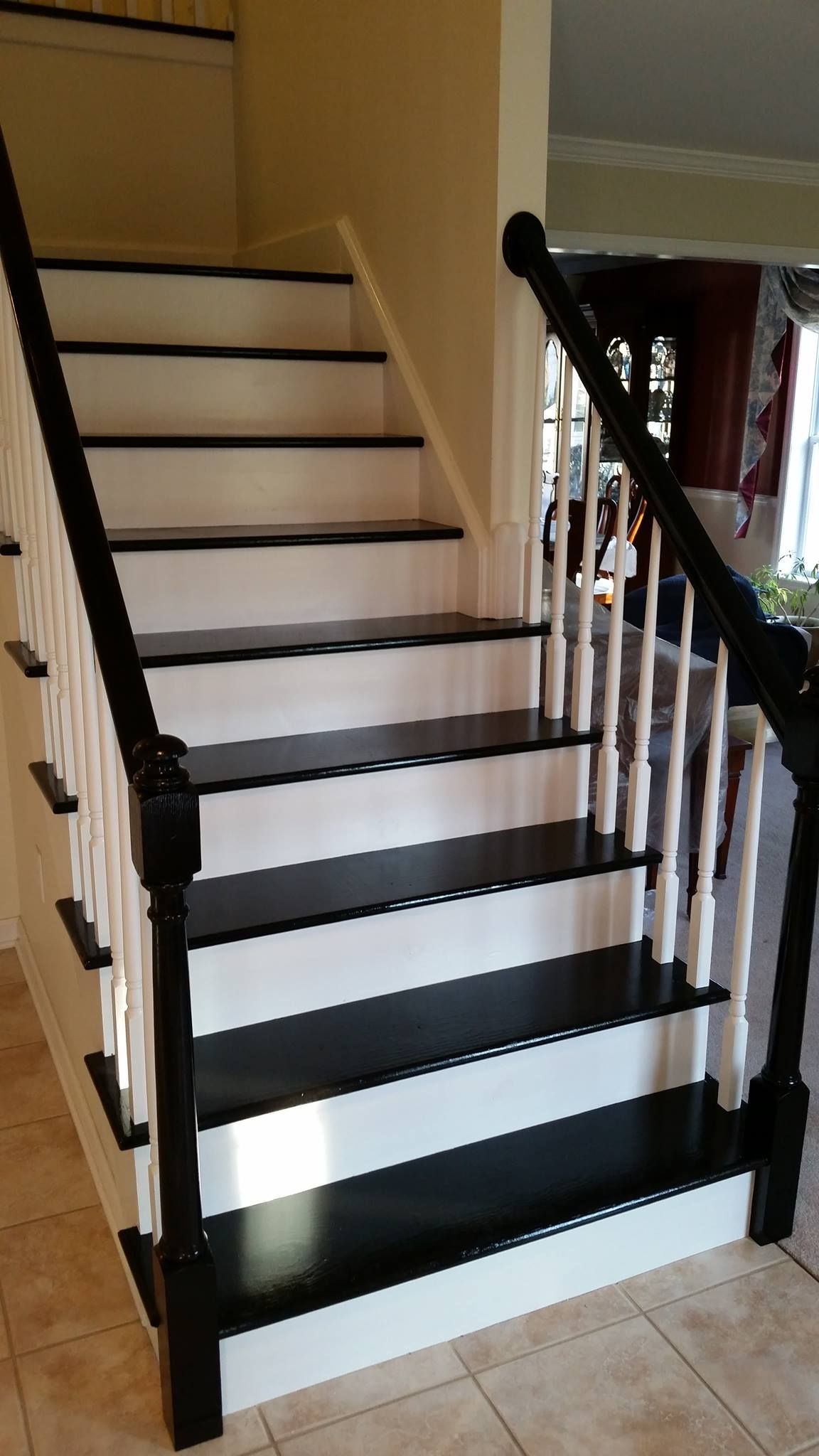A black and white staircase with a black railing in a living room.
