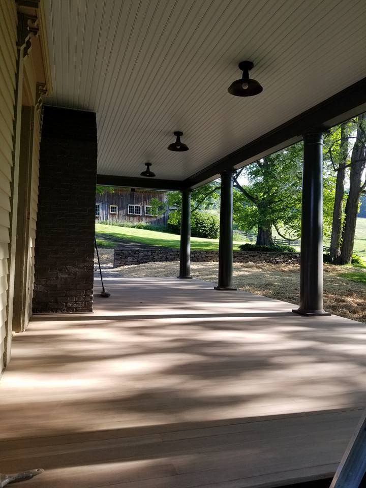 A large porch with a ceiling fan and a view of a house.