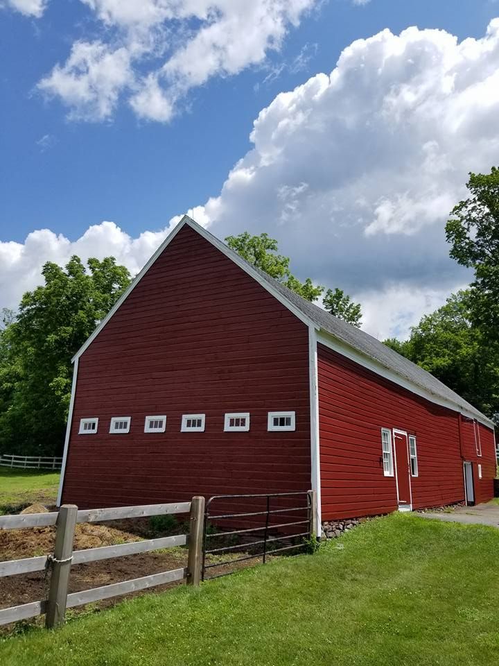 A large red barn is sitting in the middle of a grassy field.