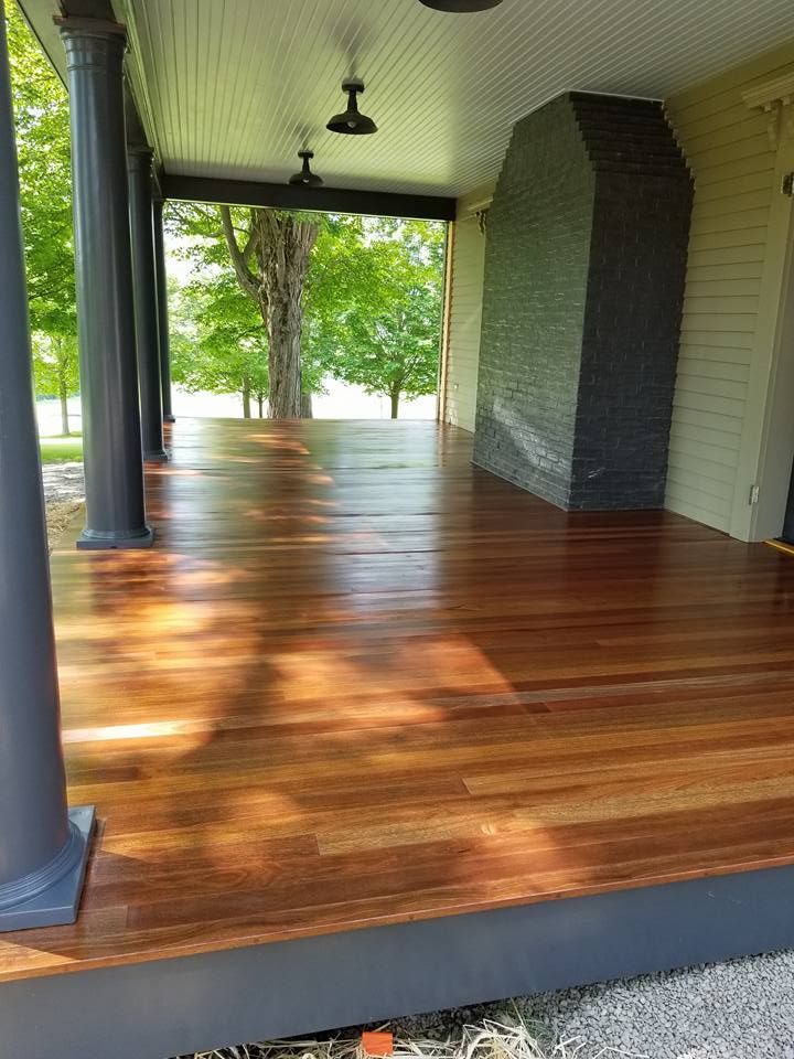 A wooden porch with a fireplace and a ceiling fan.