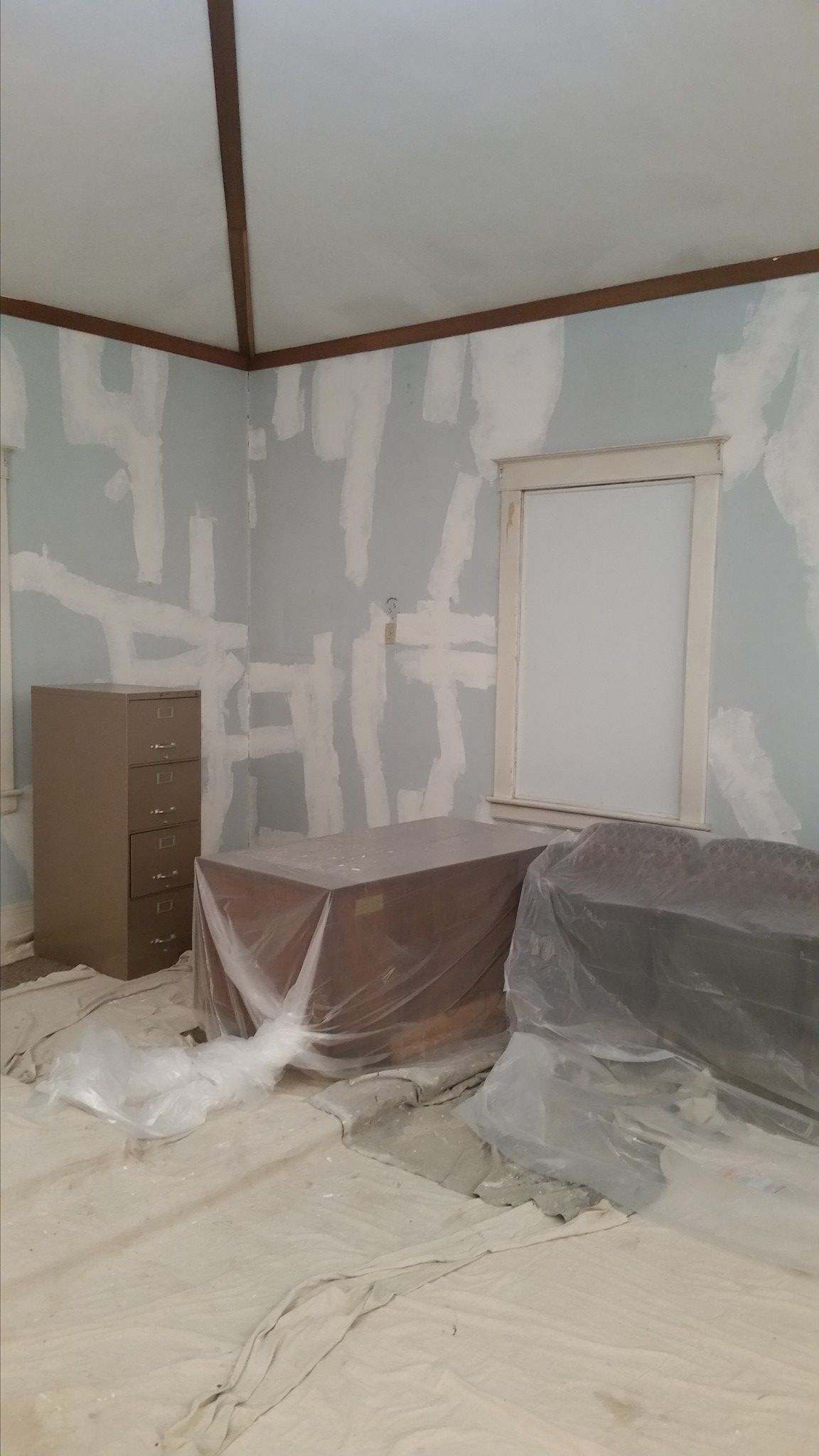 A room with a dresser and a window is being painted.