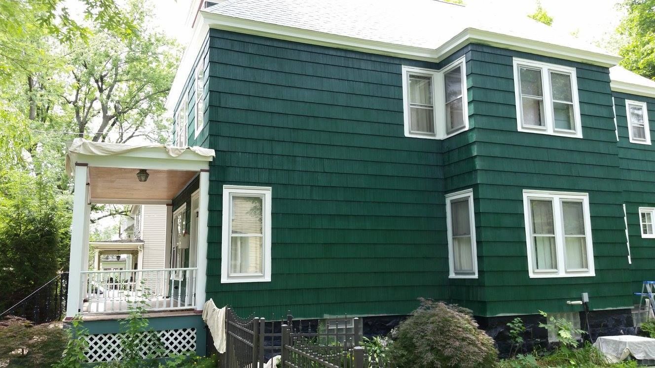 A green house with white windows and a porch.