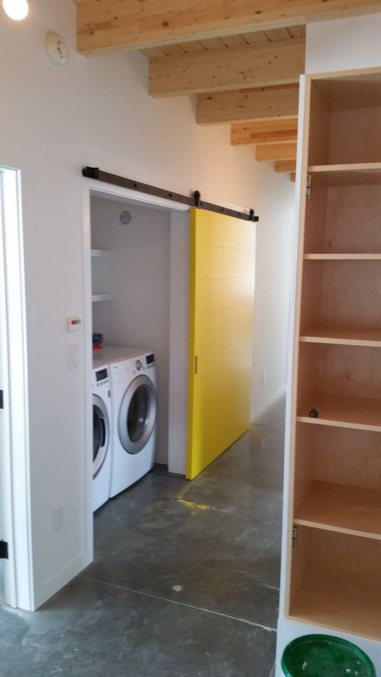 A laundry room with a washer and dryer and a yellow door