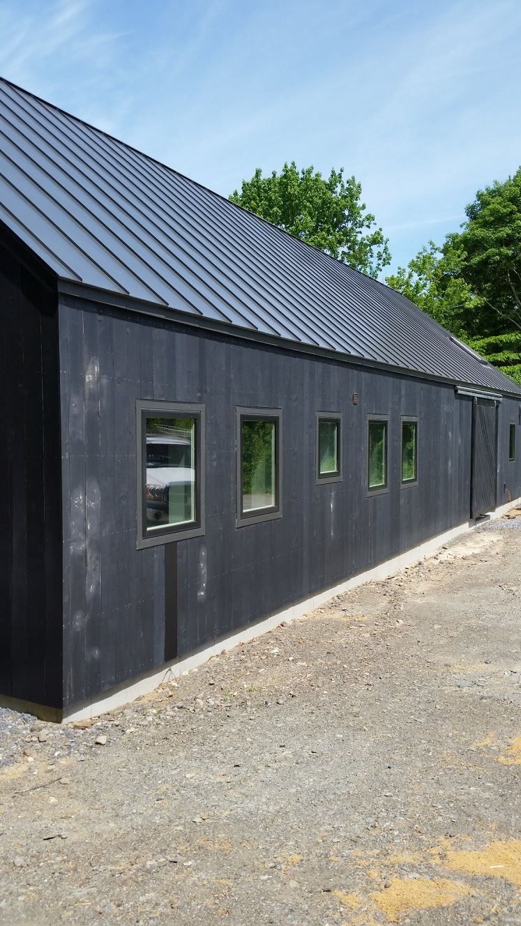 A black building with a metal roof and a lot of windows.
