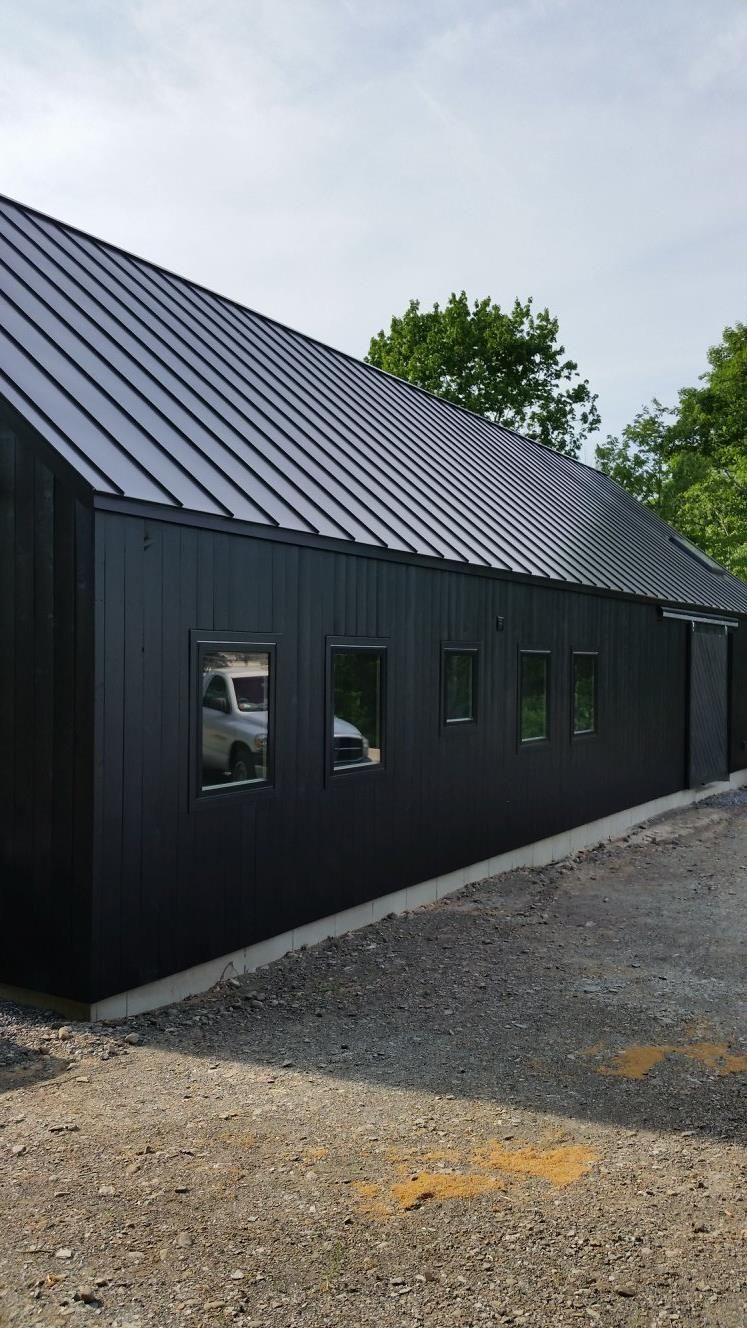 A black building with a metal roof and a lot of windows.