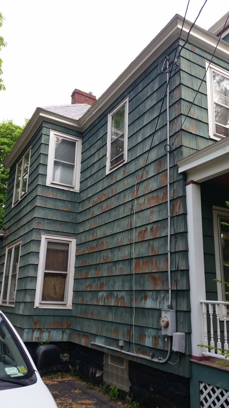 A blue house with a white car parked in front of it.