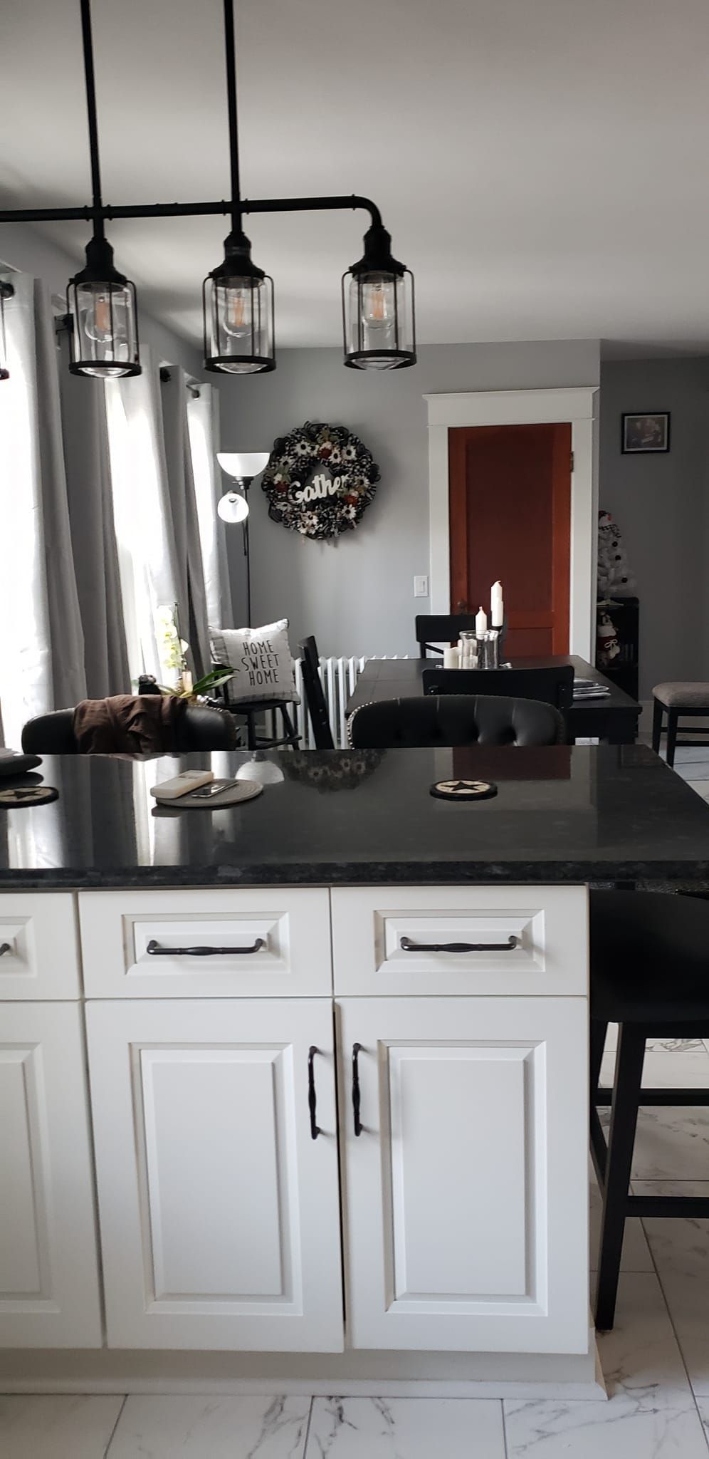 A kitchen with white cabinets and a black counter top.