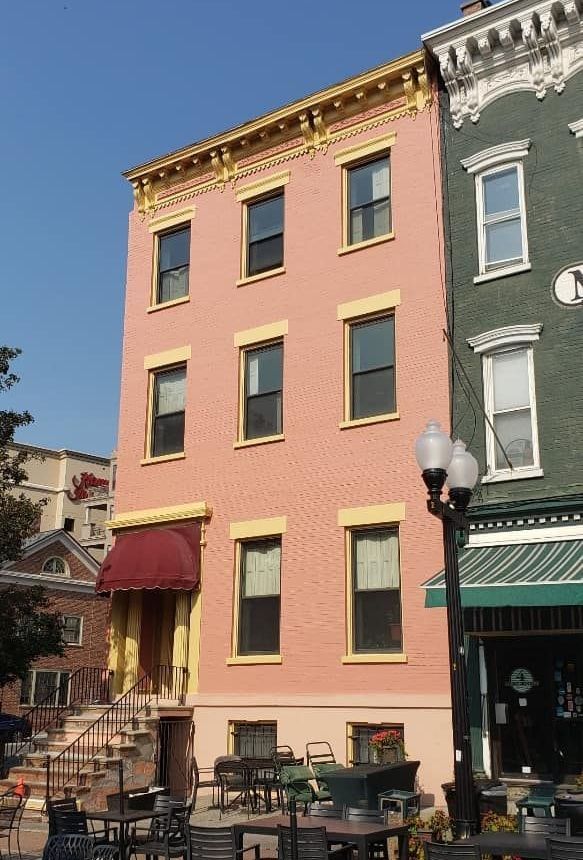A pink building with a red awning is next to a green building