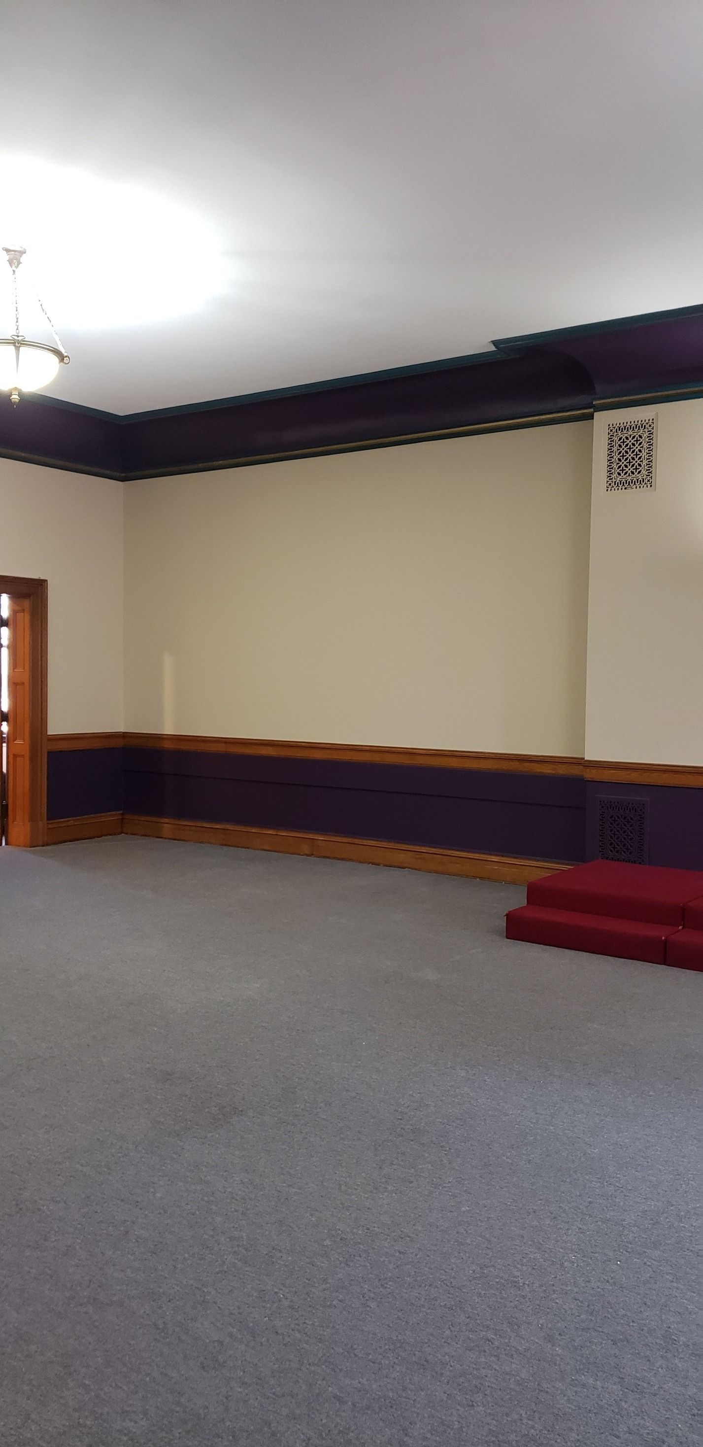 A large empty room with a red carpet and stairs.
