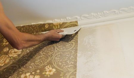 A person is applying wallpaper to a wall with a spatula.