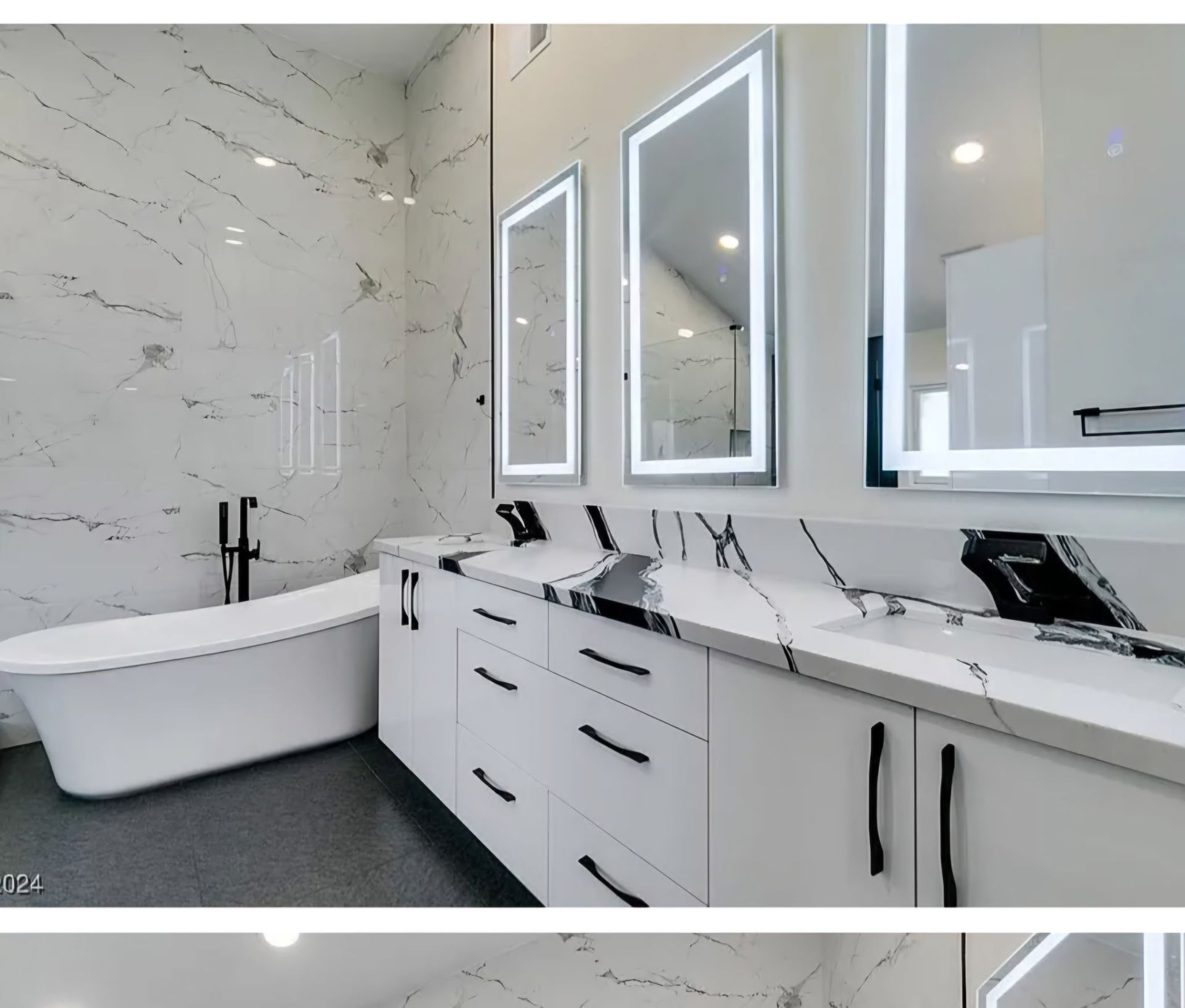 Modern white bathroom with a freestanding tub, marble countertop, and lit mirrors.