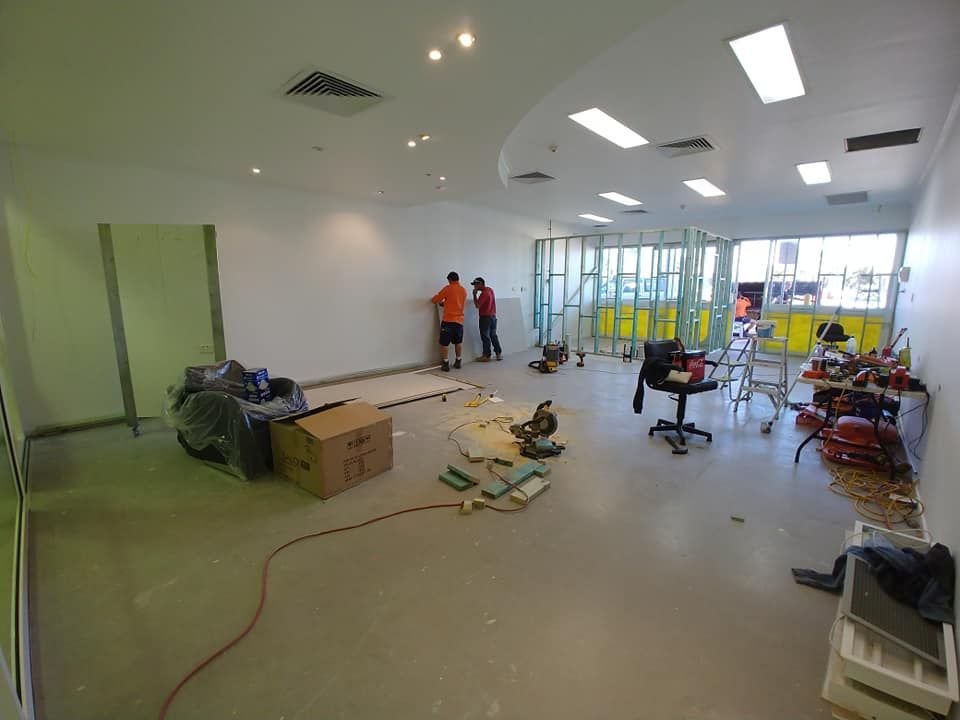 A Group of People Are Working in A Large Room — Your Local Handywoman in Burnett Heads, QLD