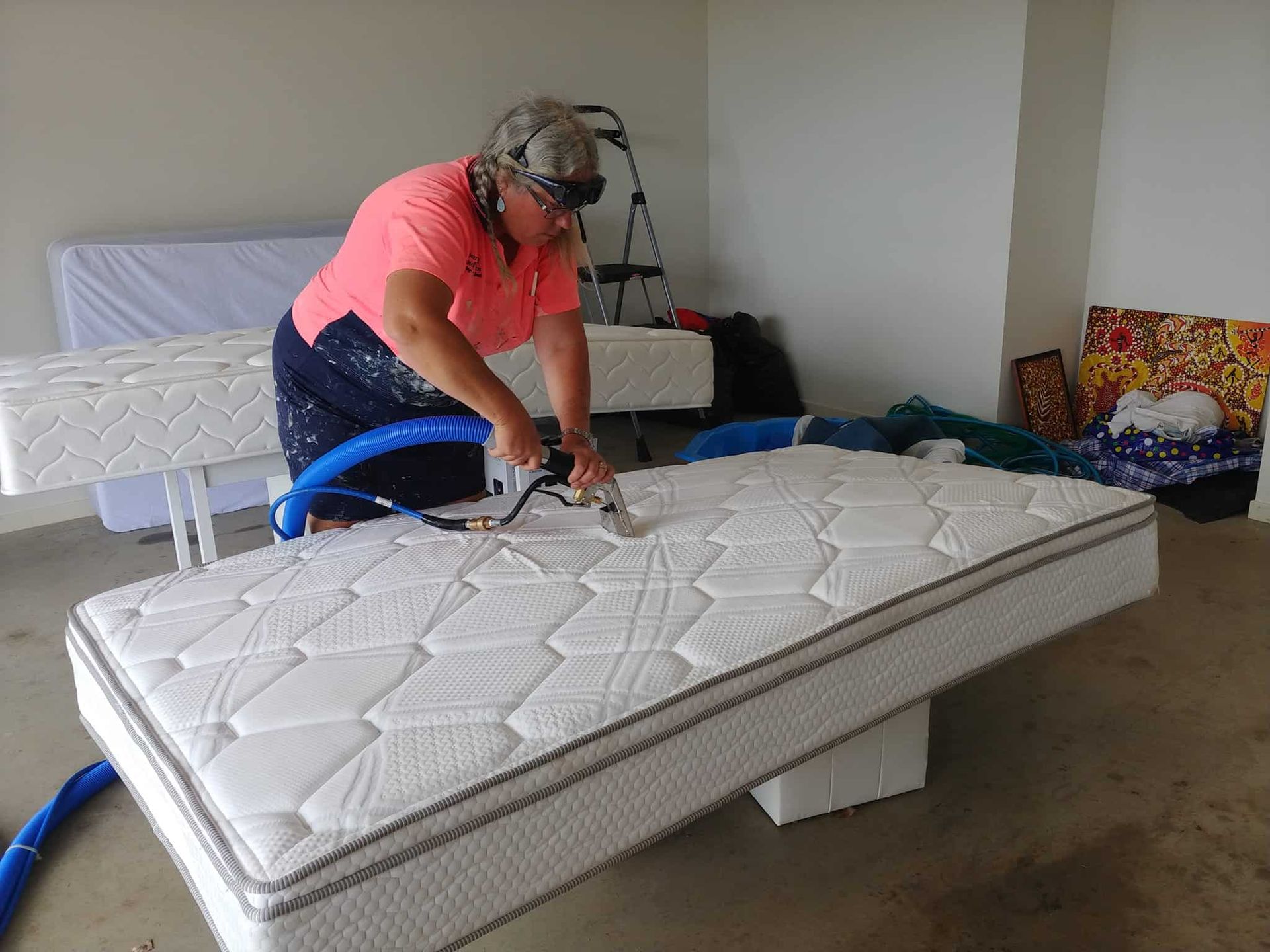 A Woman Is Cleaning a Mattress with A Vacuum Cleaner — Your Local Handywoman in Burnett Heads, QLD