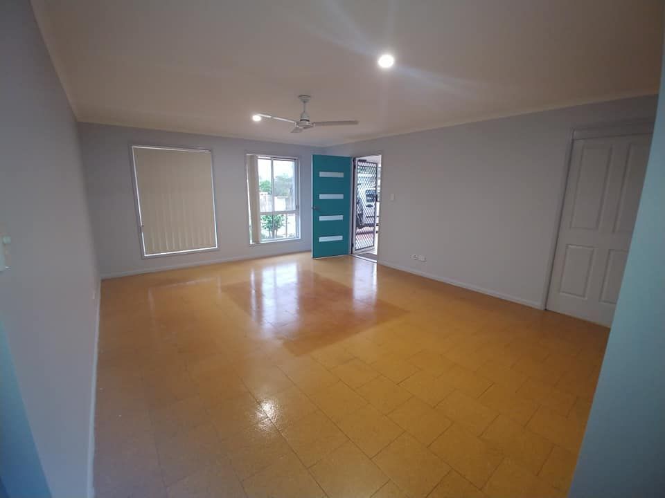 An Empty Living Room with A Ceiling Fan and A Blue Door — Your Local Handywoman in Burnett Heads, QLD