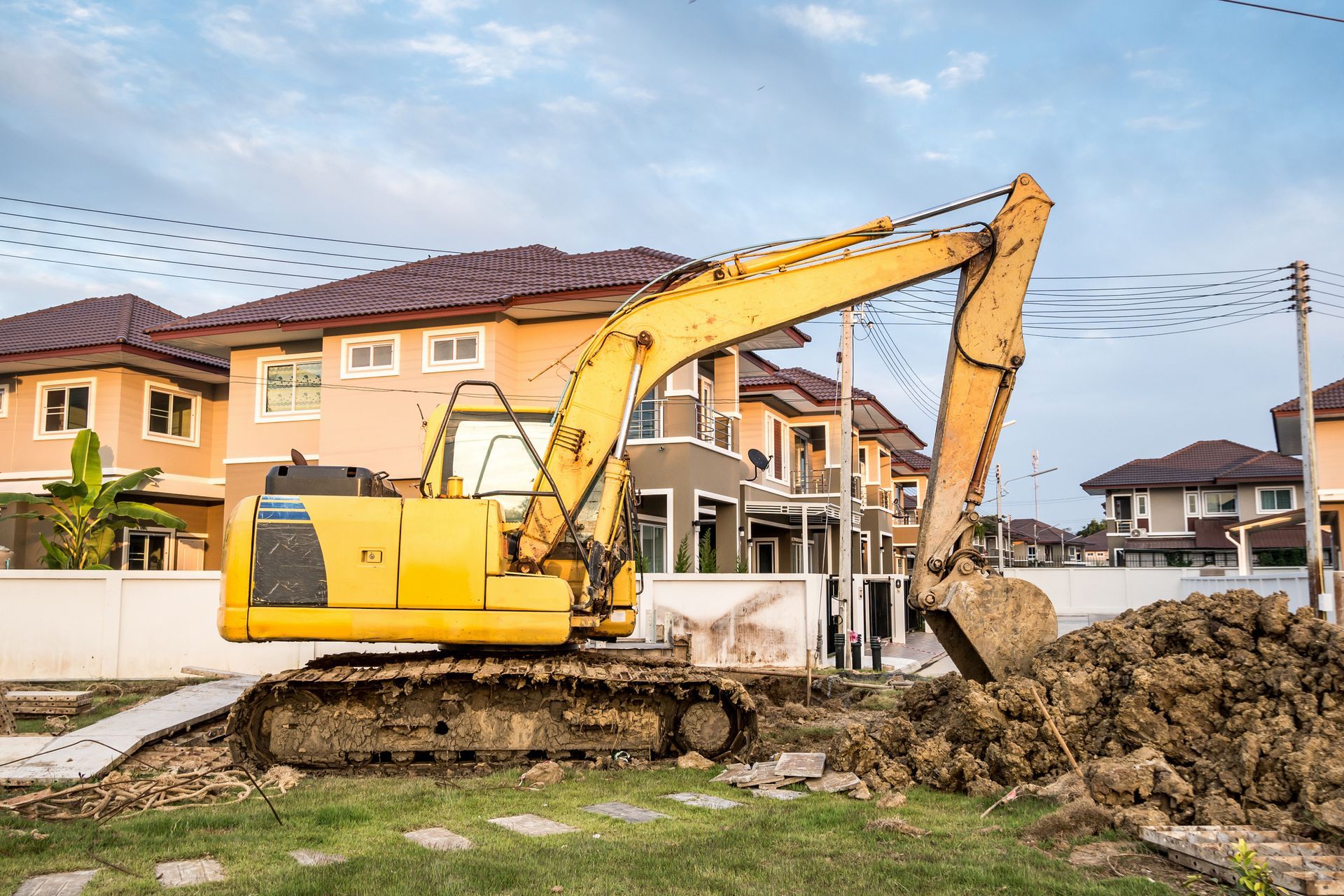 Yellow backhoe excavator at house construction site.