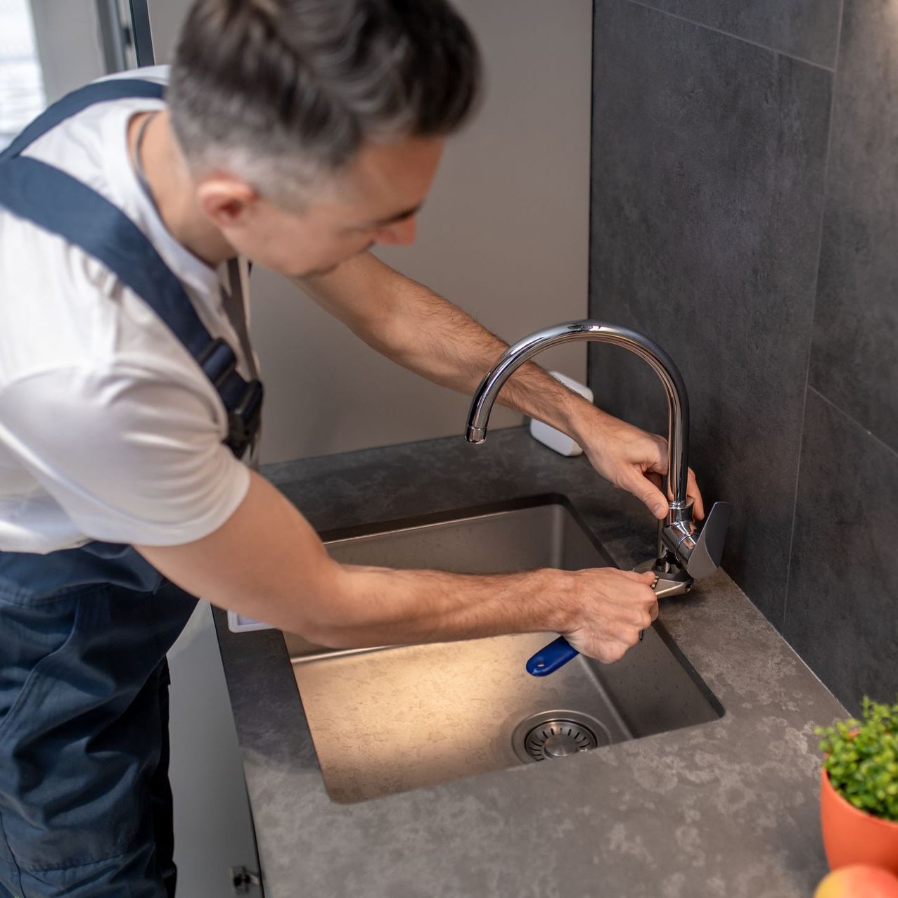 professional plumber installing new kitchen sink during renovation