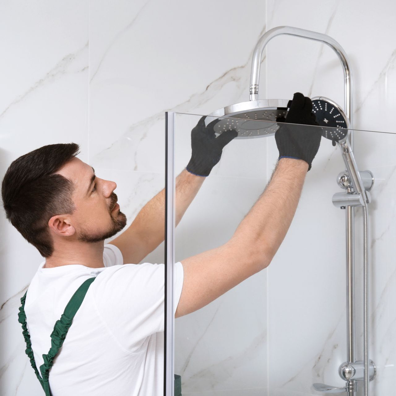 plumber installing new modern shower head during bathroom renovation project