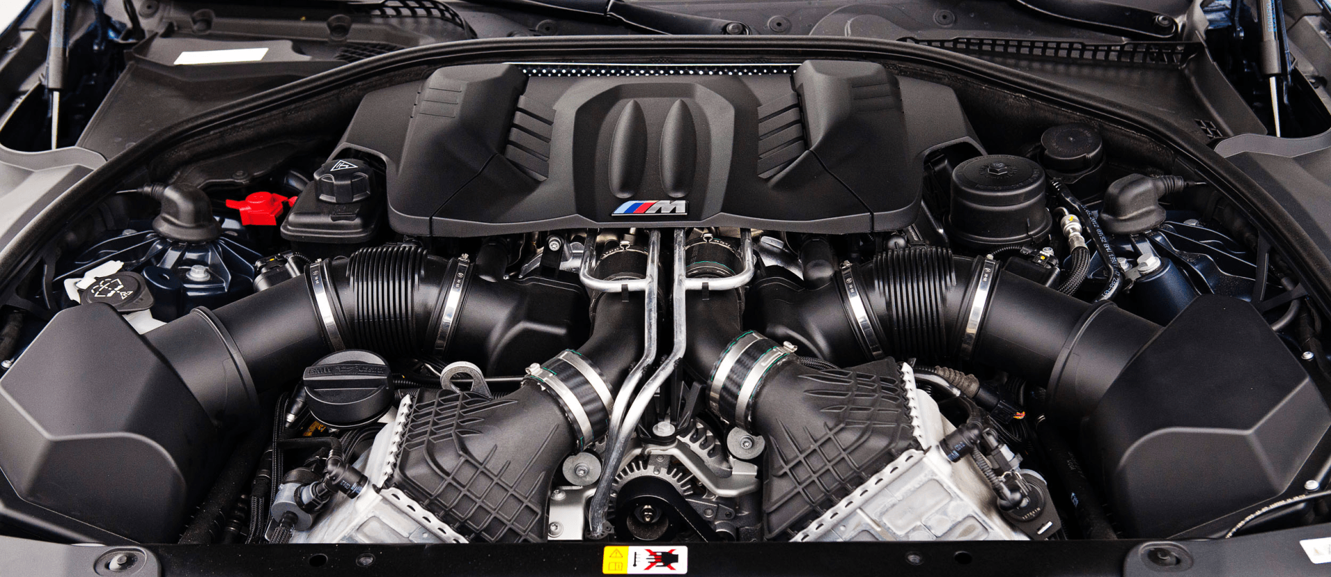 Close-up of a car engine bay, showing black air intakes, components, and the 