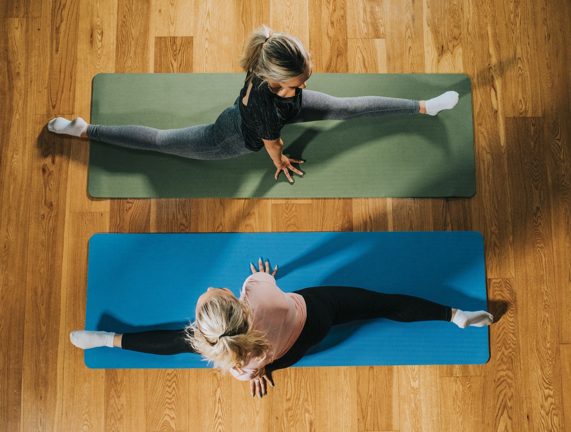 Two people doing splits on yoga mats.