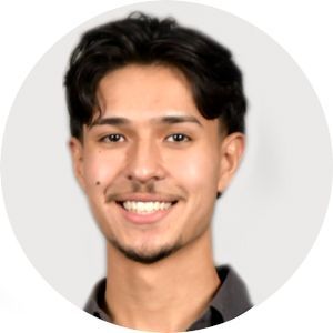Smiling person with dark hair, a light complexion, and a gray shirt against a white background.