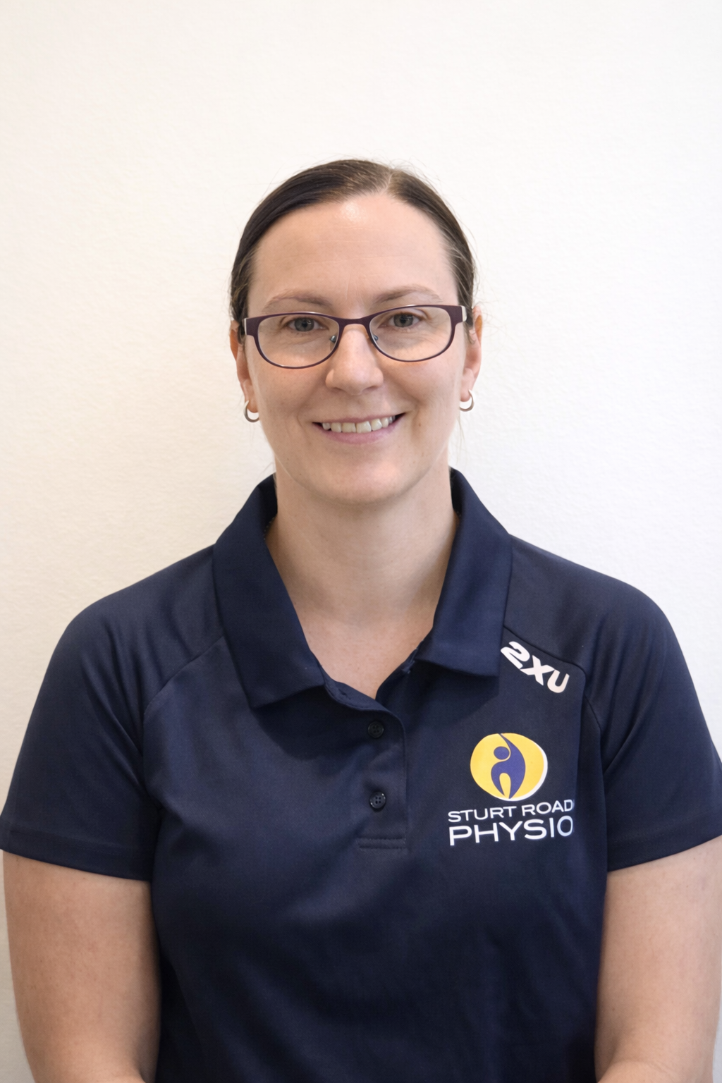Man with short brown hair, smiling, wearing a blue polo shirt, against a white background.