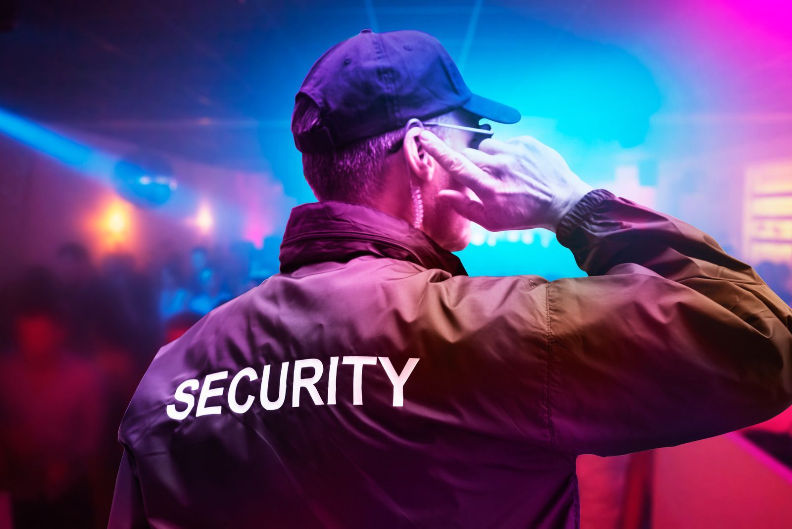 A security guard is covering his ears in a nightclub.