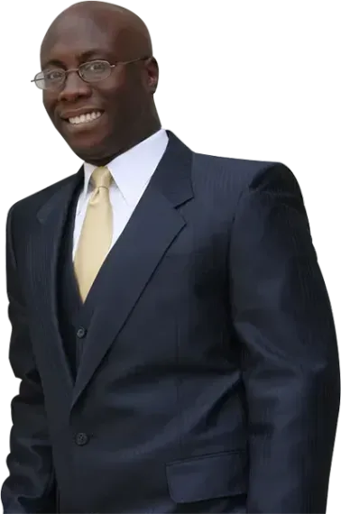 A smiling person in a dark suit, gold tie, and glasses against a white background.