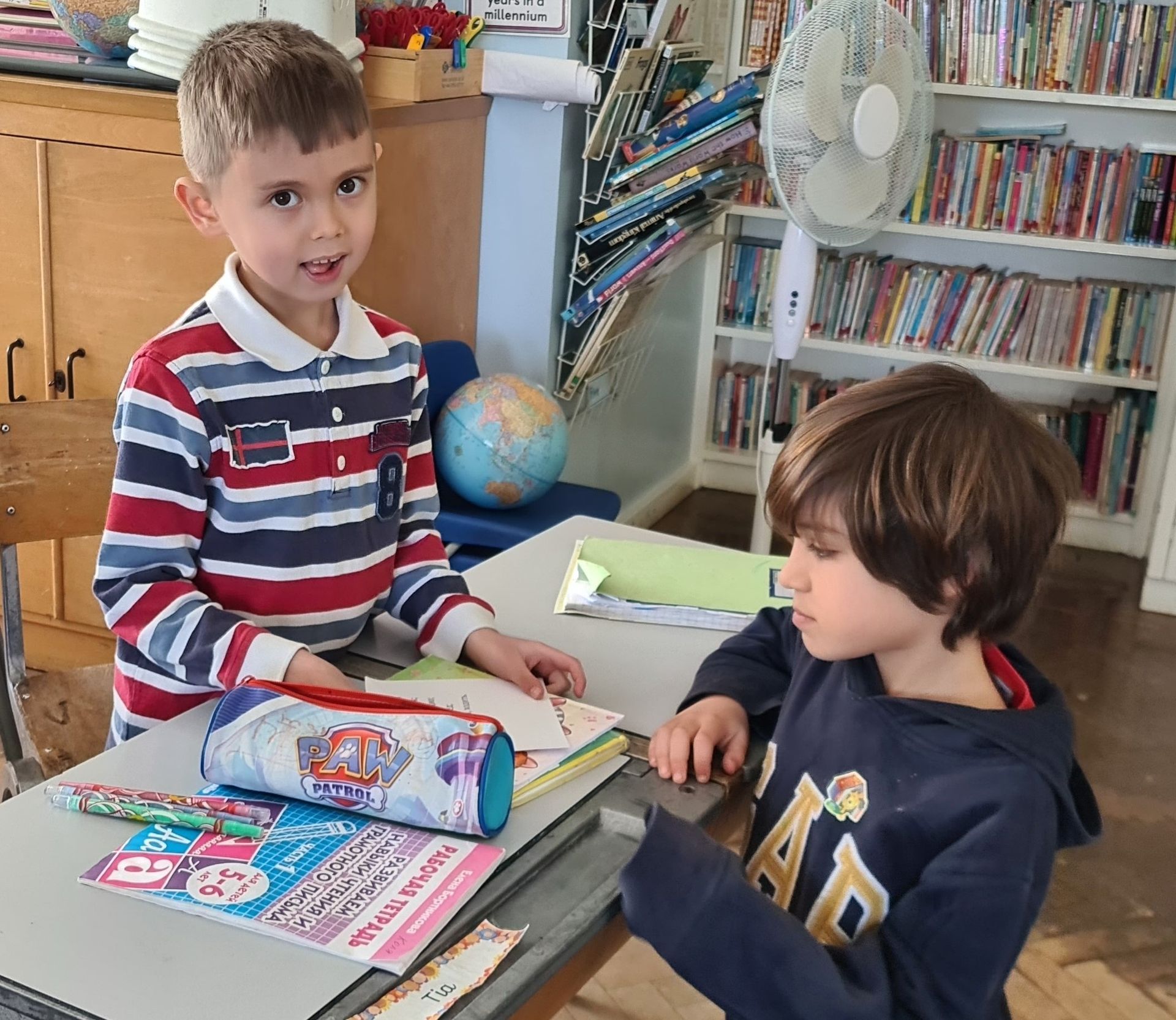 Двое мальчиков сидят за партой в классе.