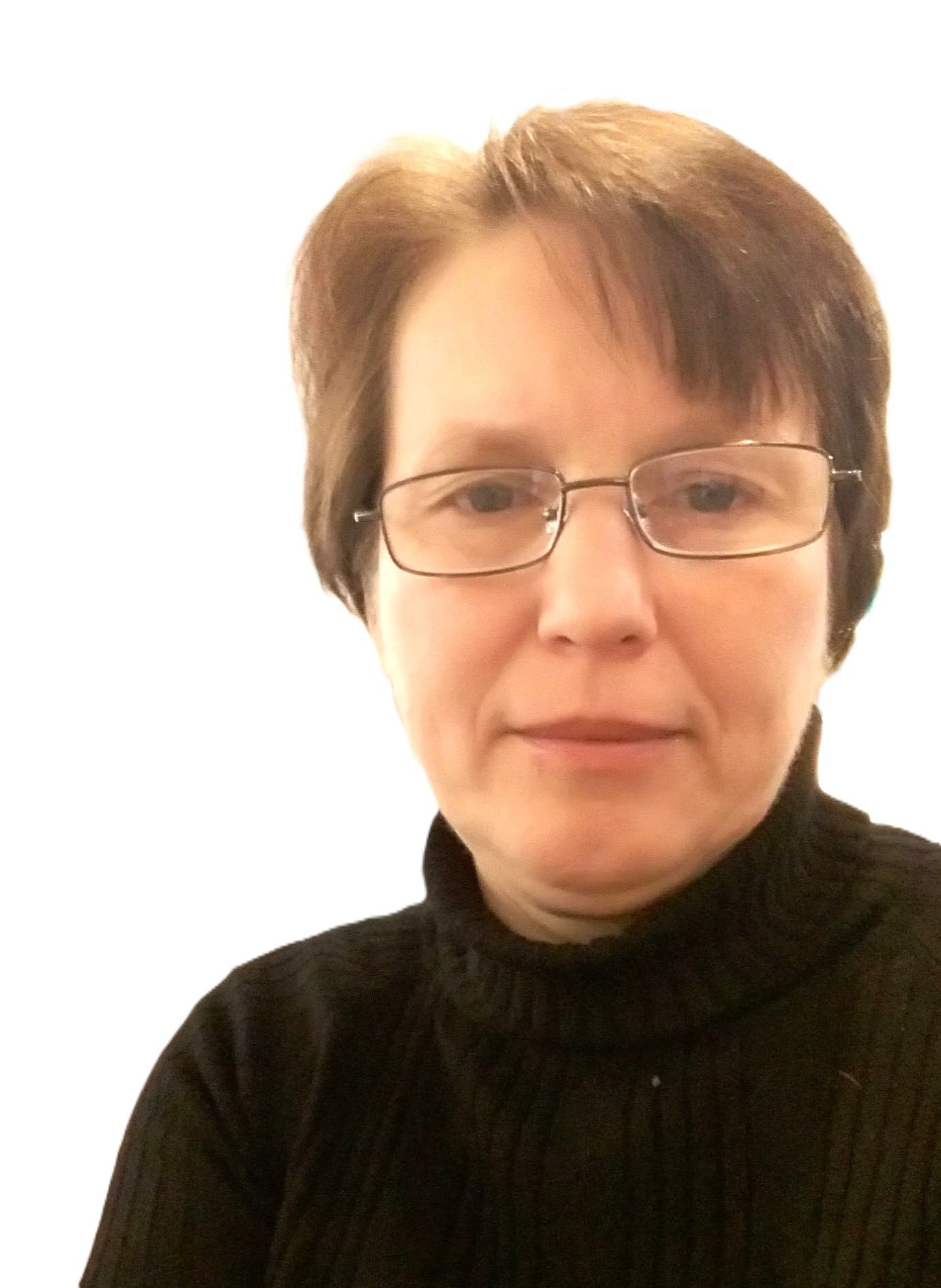 Женщина в очках и черной водолазке смотрит в камеру