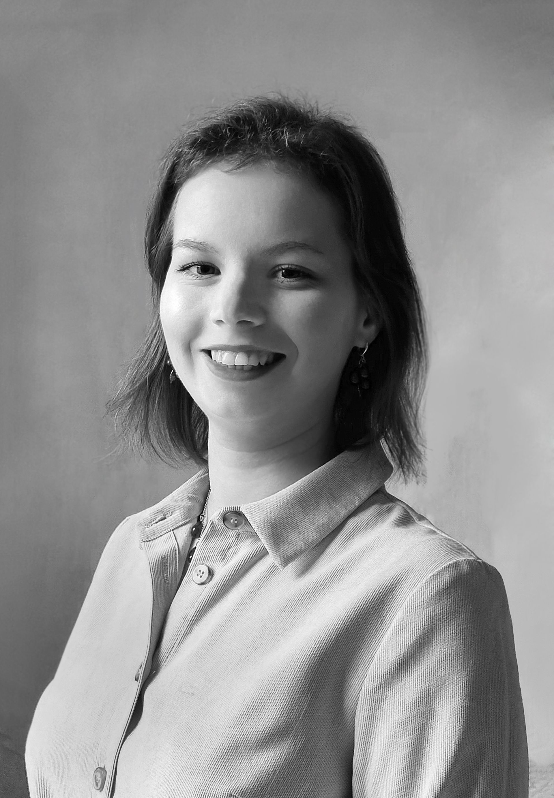 На черно-белой фотографии улыбается женщина в полосатой рубашке.