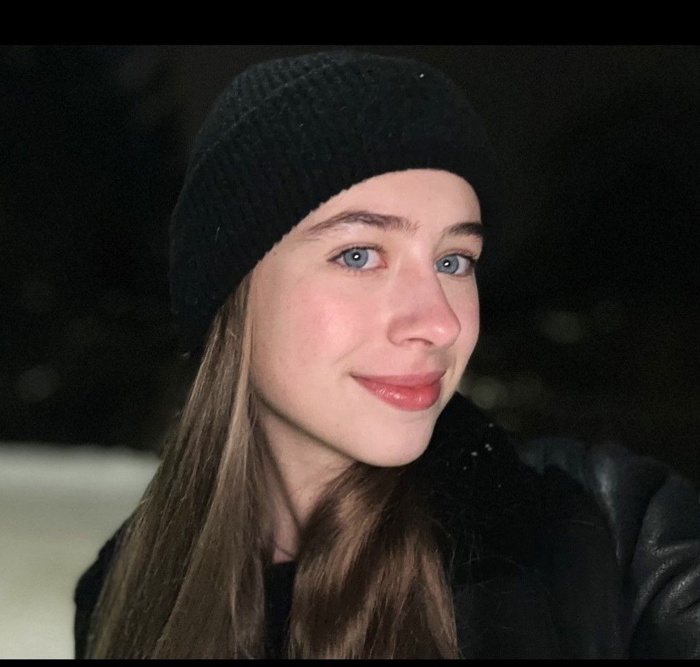 Молодая женщина в черной шапке и черной куртке