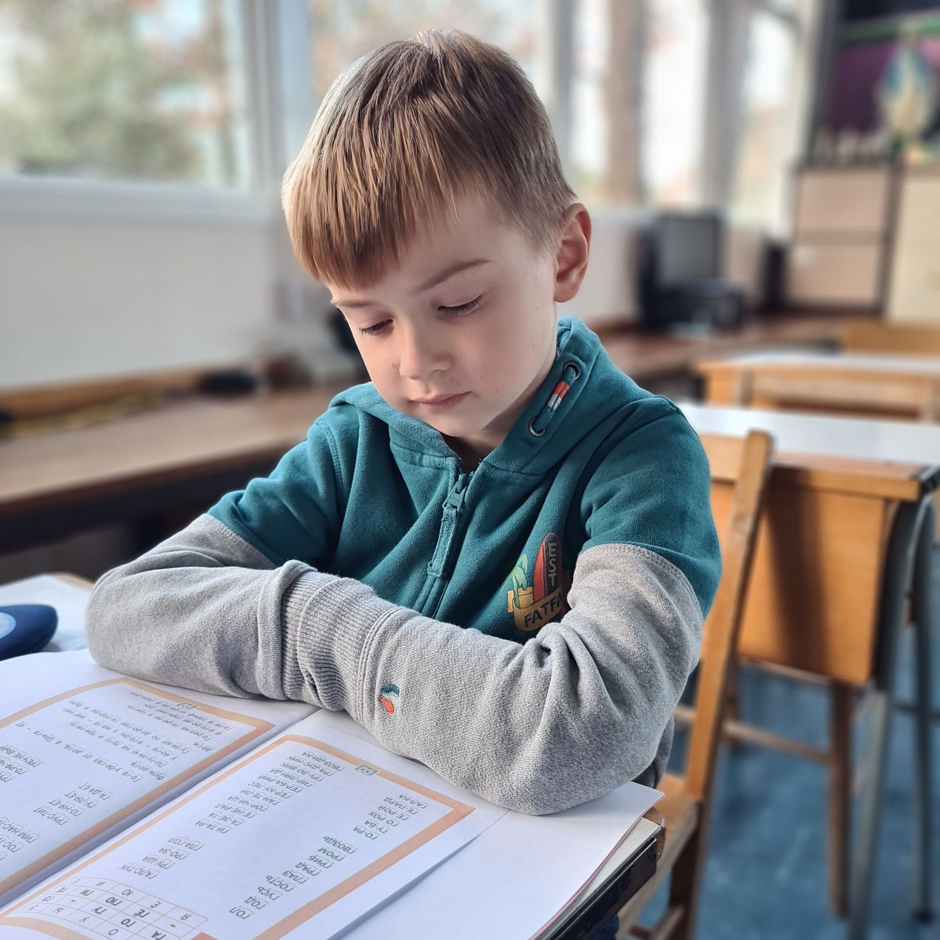 Мальчик в зеленой рубашке читает книгу в классе