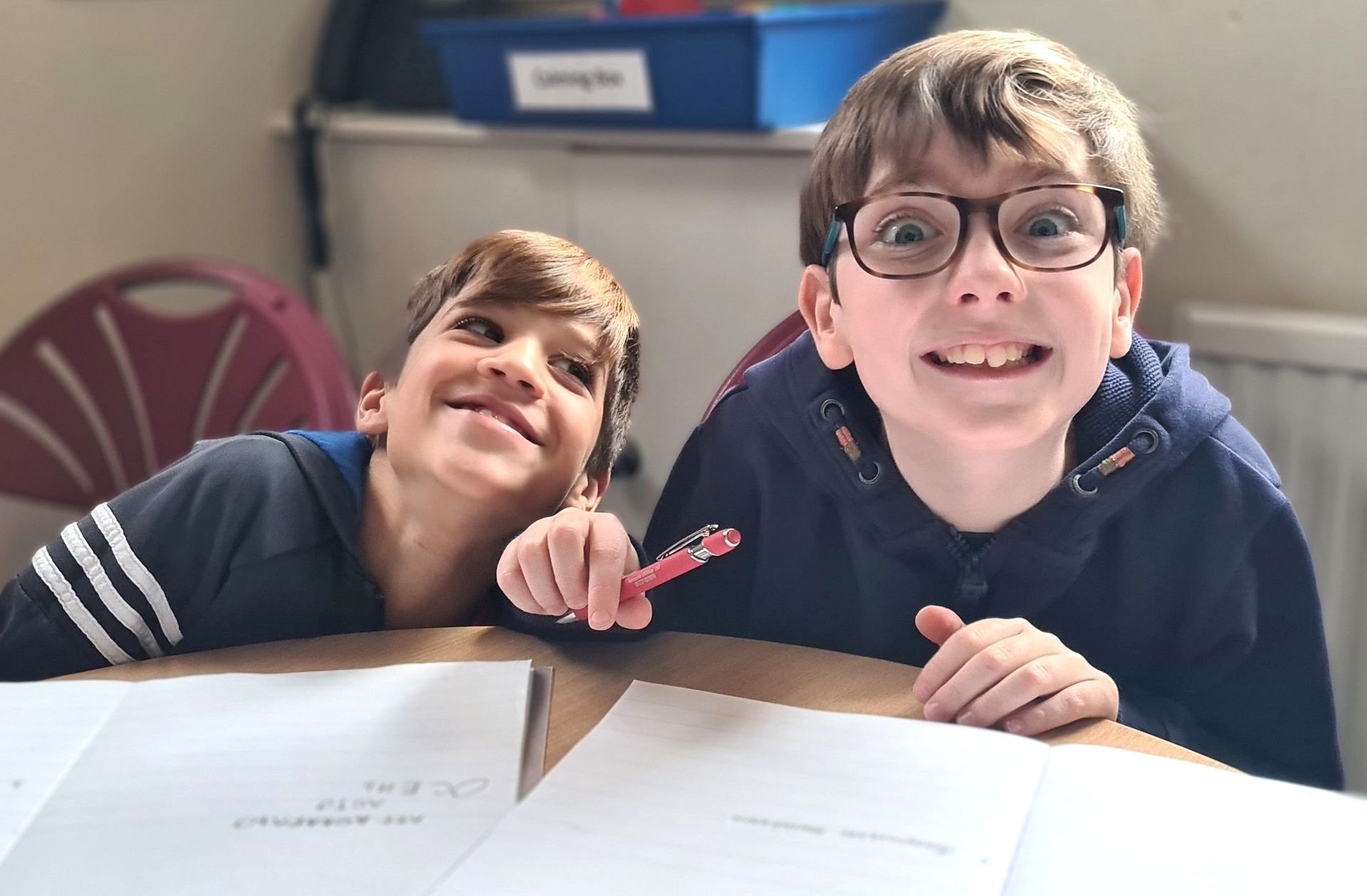 Двое молодых парней сидят за столом и улыбаются в камеру.