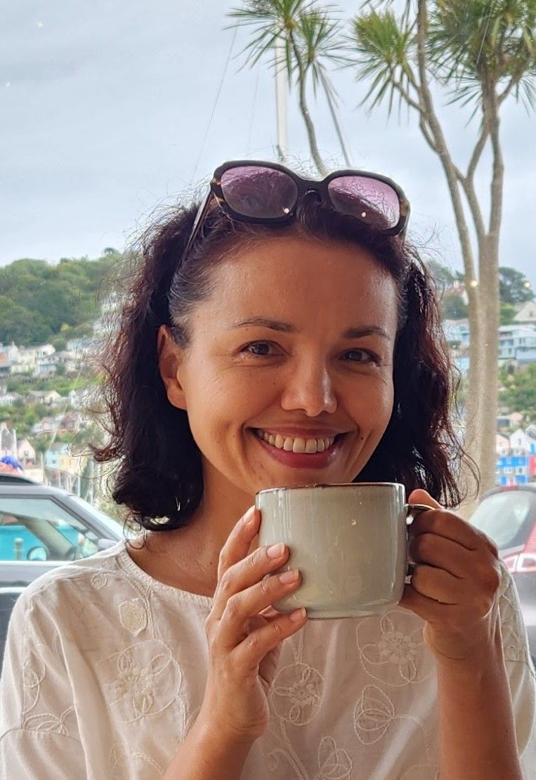 Женщина улыбается, держа чашку кофе.