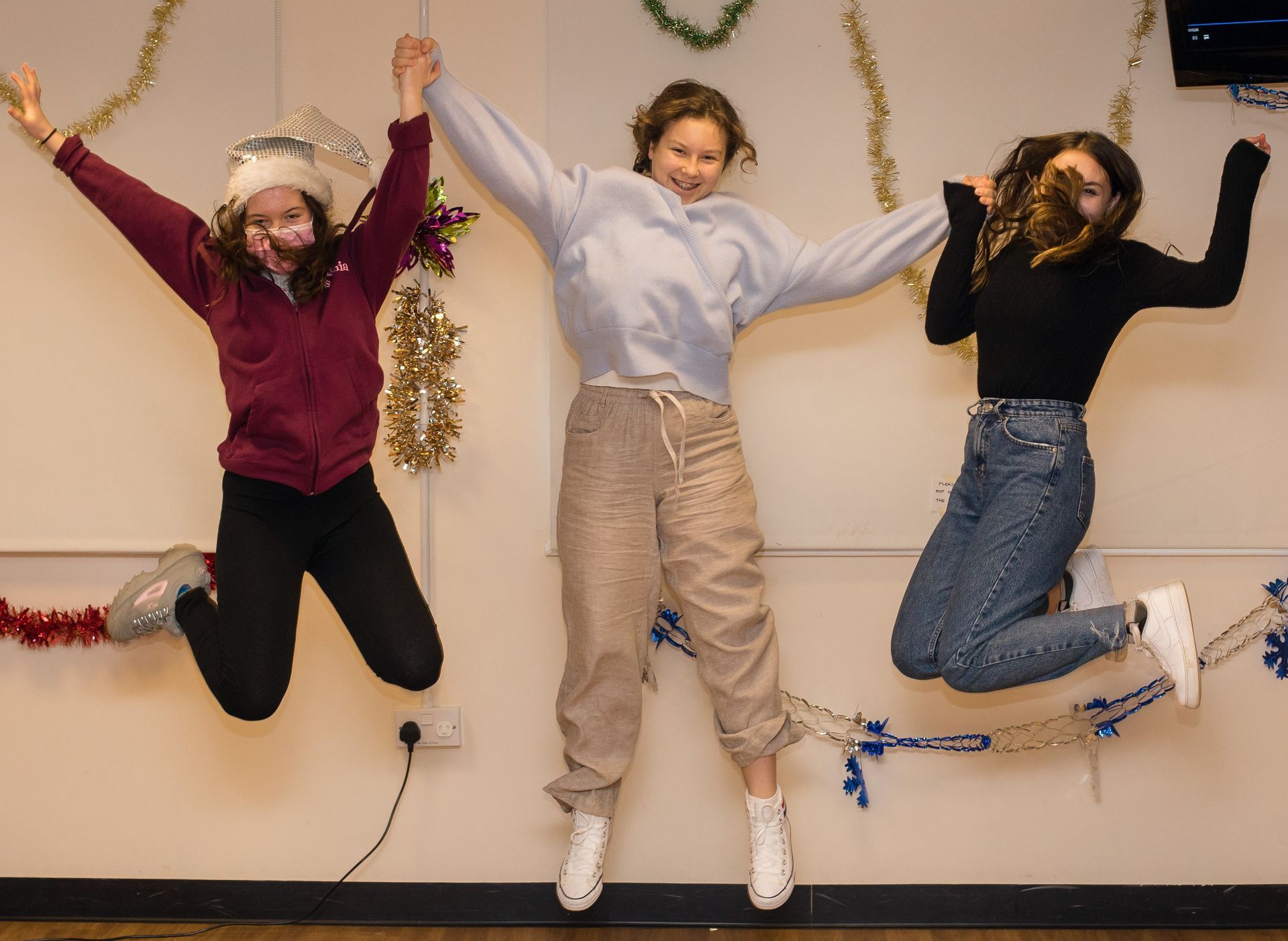 Три девочки подпрыгивают в воздухе, подняв руки вверх