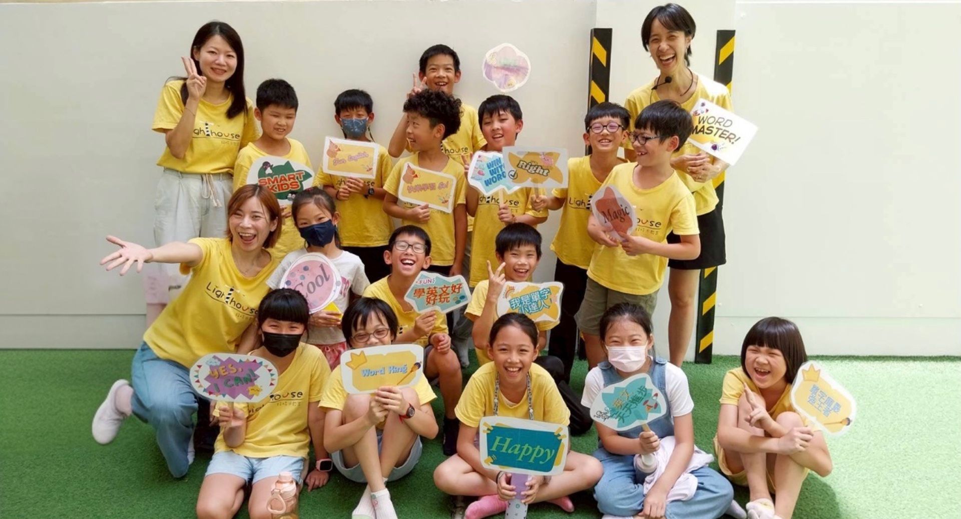 一群穿著黃色襯衫的孩子和大人舉著標語,帶著笑容地在戶外。