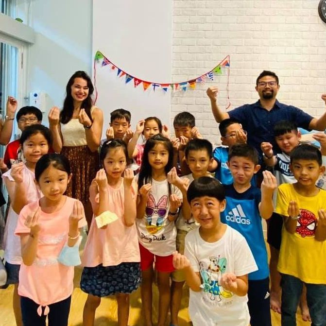 一群孩子和兩個大人正在慶祝。他們在室內,舉著色彩鮮豔的橫幅,高舉拳頭。